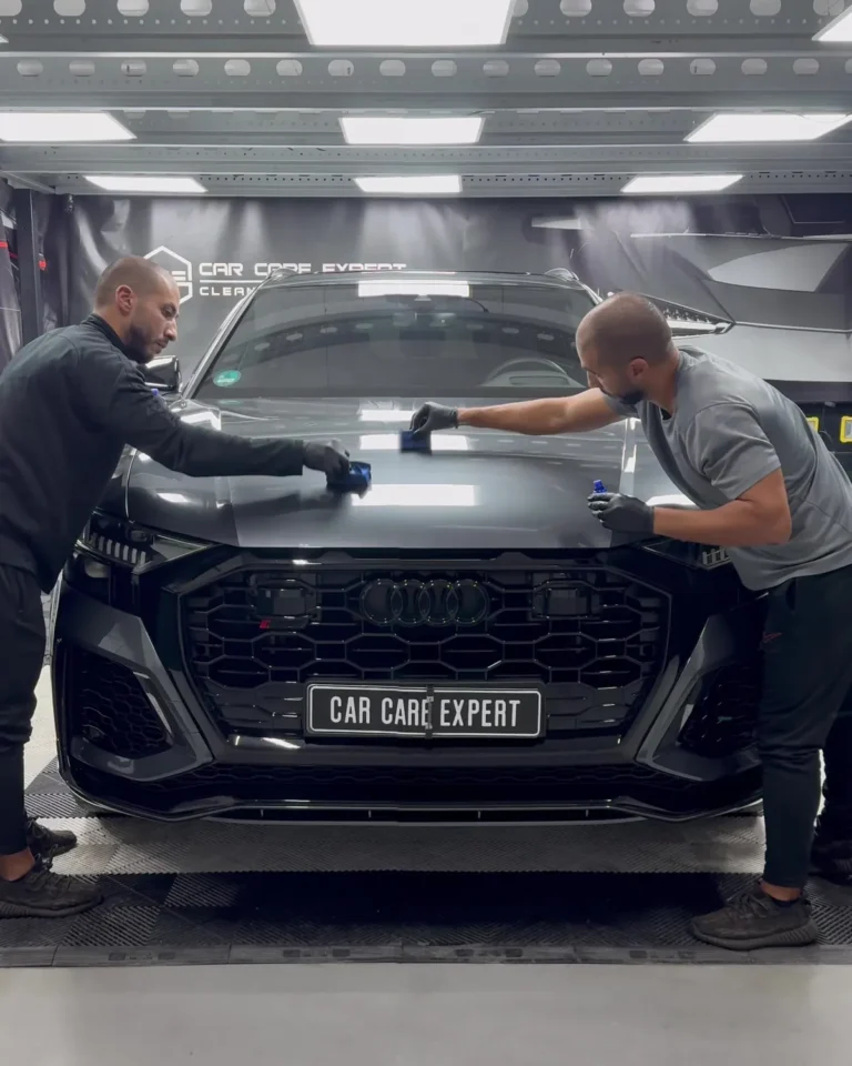 Twee medewerkers van Car Care Expert brengen glascoating aan op de motorkap van de Audi RS Q8