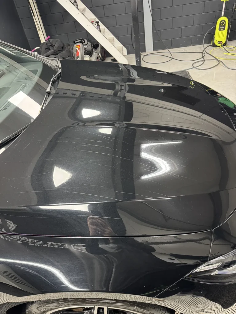 Krassen op de motorkap van de Mercedes-Benz CLA van opzij gezien, voor het polijsten